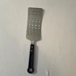 Farberware Perforated Stainless Steel Turner With Plastic Handle. Fixed Price $24.00.